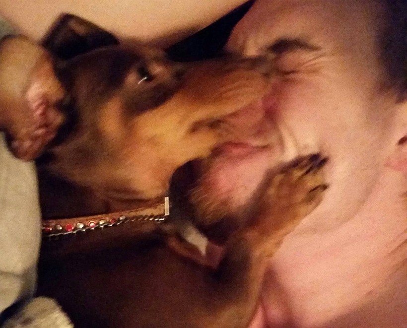 Boo the dachshund licking Wes's face while he laughs with his eyes shut